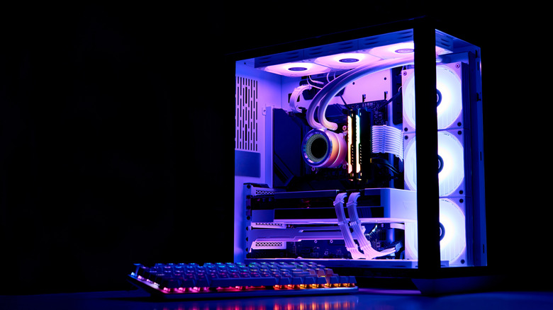 A lit-up desktop PC on a desk with a keyboard.